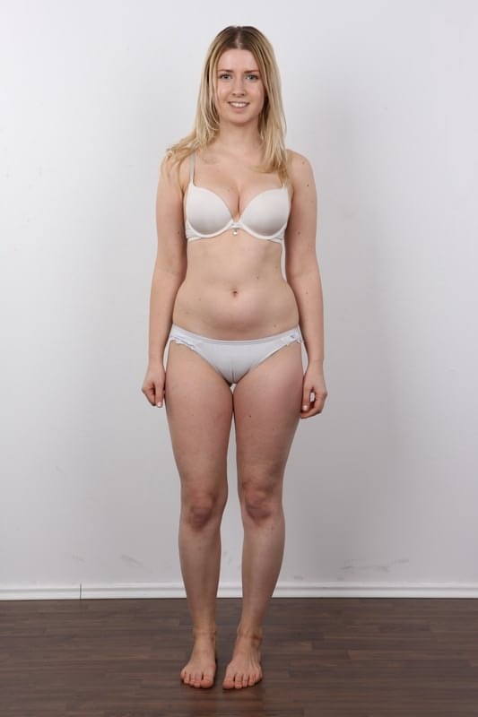 Blonde girl removes a sweater and jeans before standing naked for the first time