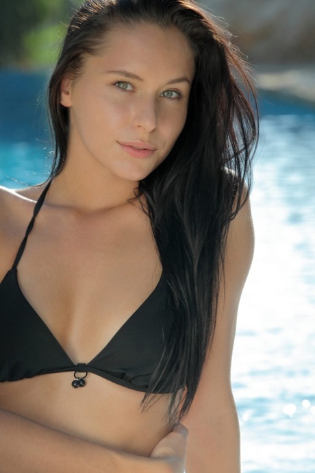 Brunette female Mira removes a black bikini while stretching out by a pool