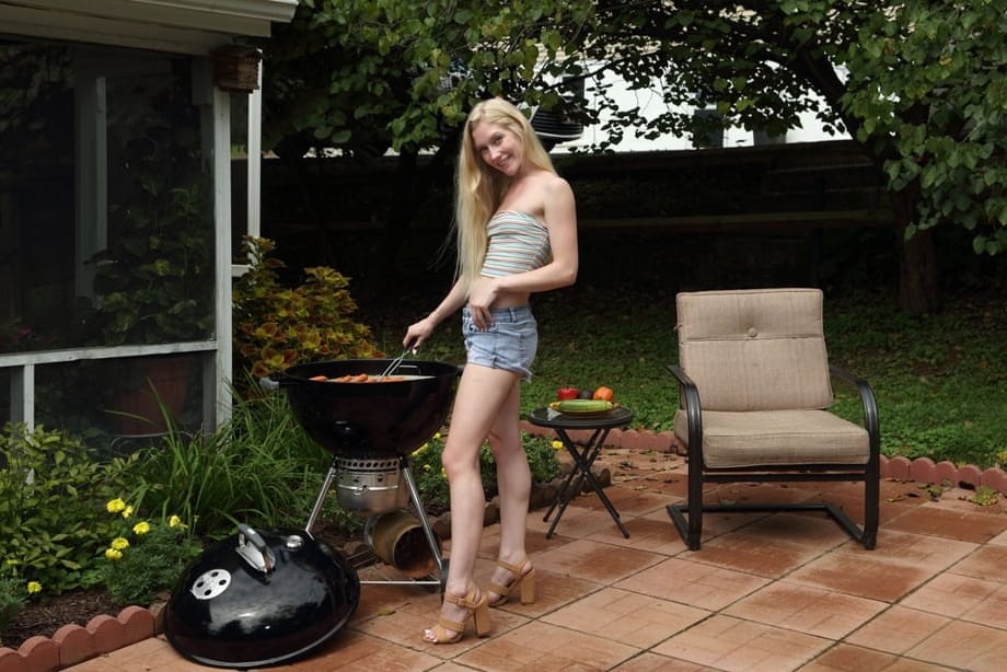 Emma Starletto, bionda arrapata, che si infila un cetriolo spesso e lungo nella sua figa bagnata sul patio inondato dal sole - 1