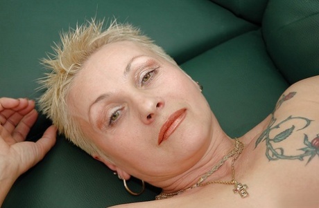 Short haired tattooed granny with pierced nipples taking off her lingerie