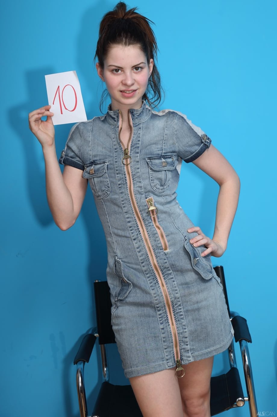 Enticing gal Judy Smile takes clothes off in strange room with chairs