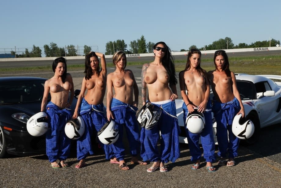 Race poses seductively with other busty racers baring big tits by sleek race cars - 12