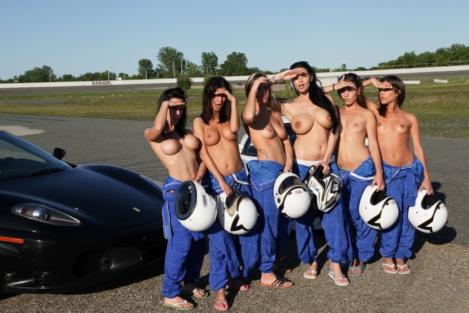 A gaggle of sexy race car drivers pose topless showing big tits by their cars