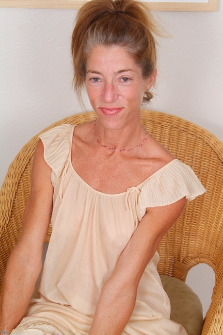 Mature Courtney poses tan-lined body teasingly on wide wicker chair - 4