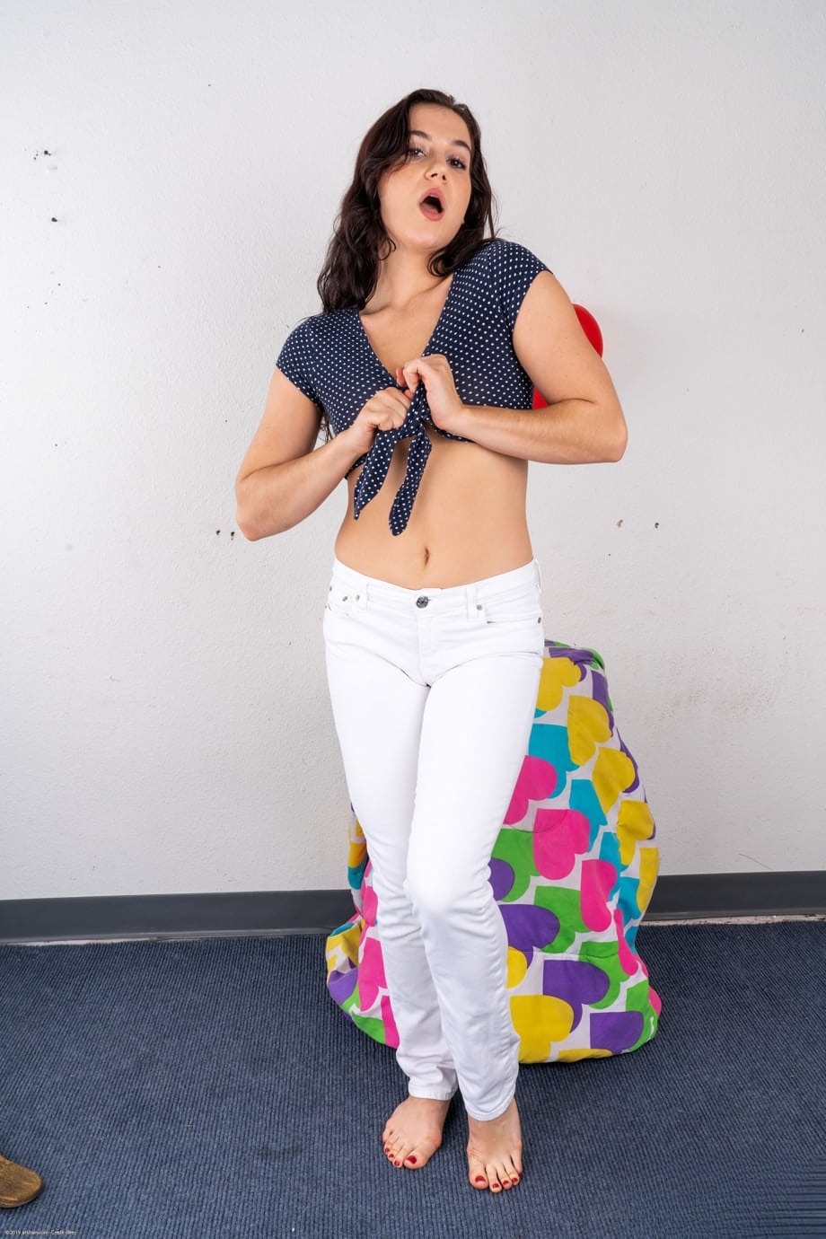 La bellissima Kasey Warner si spoglia nuda dai pantaloni bianchi, stuzzicando sul morbido pouf - 2