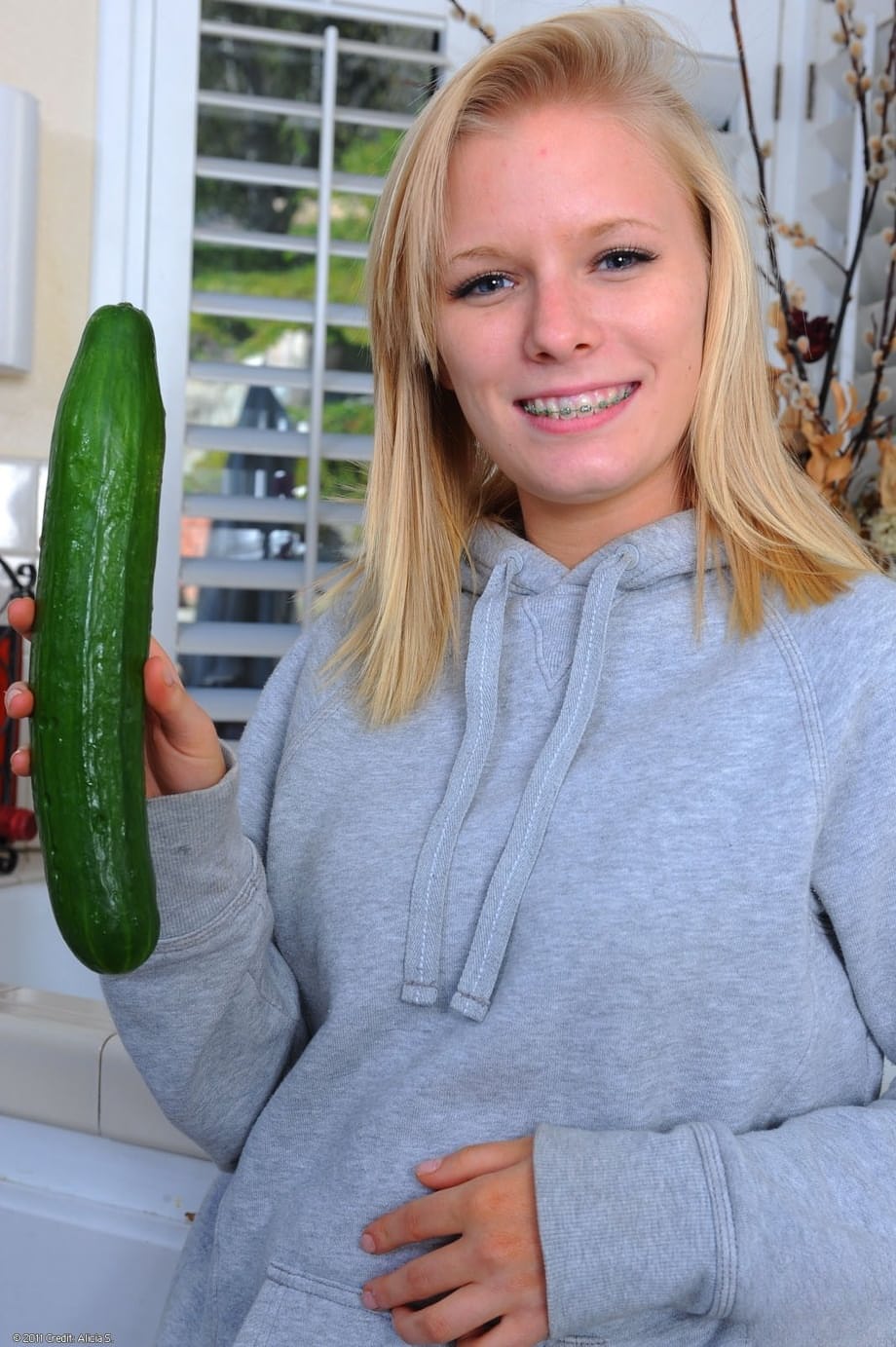 Blonde housewife Elaina Raye toys with her shaved pussy using a cucumber